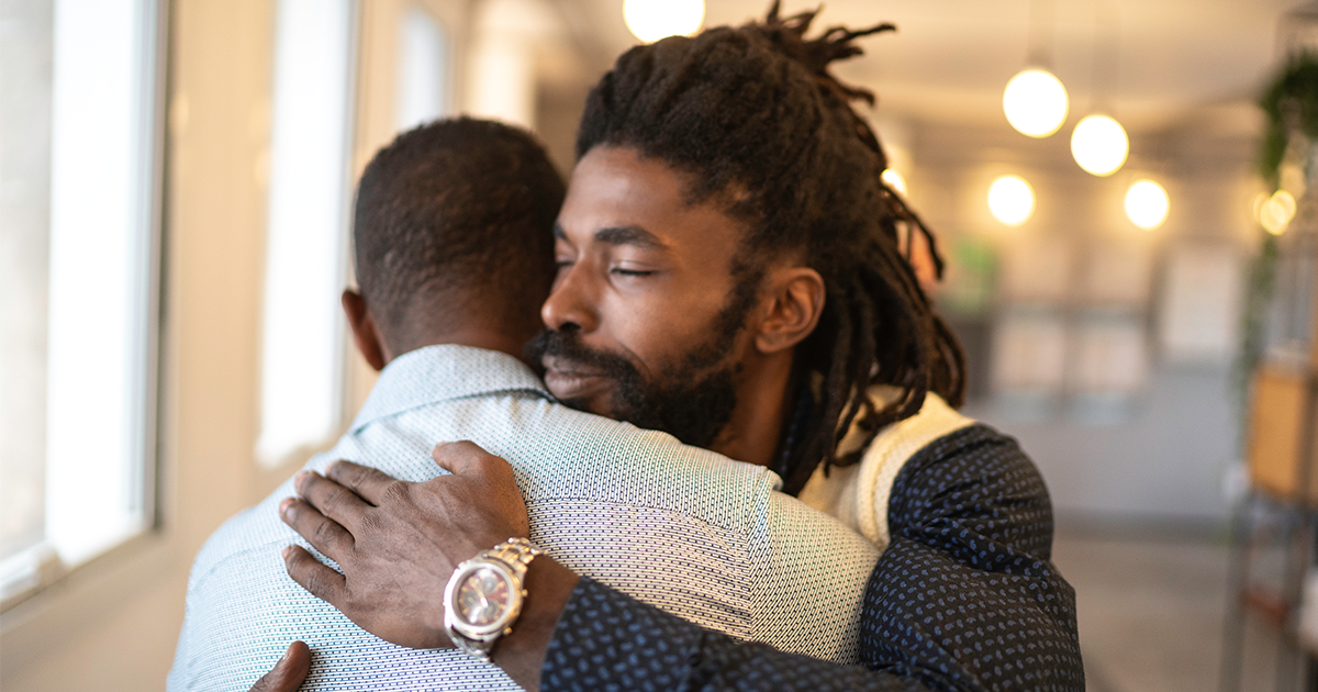 Two African-American businessmen embrace.