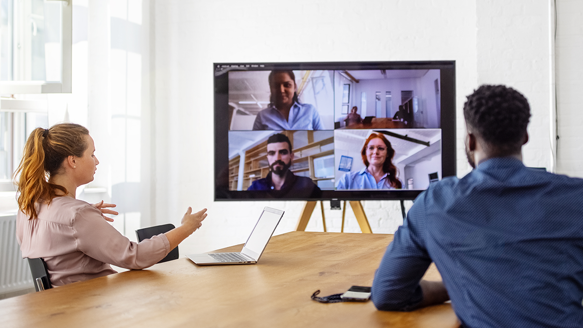 Black man and White woman sitting at a conference table on a virtual meeting with colleagues