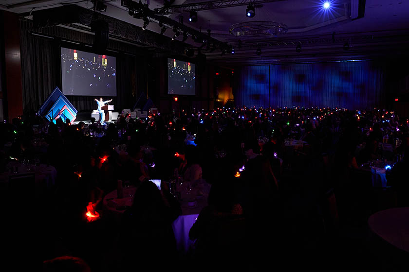 2023 Catalyst Awards dinning room darkened with small glowing bracelets on hundreds of attendees