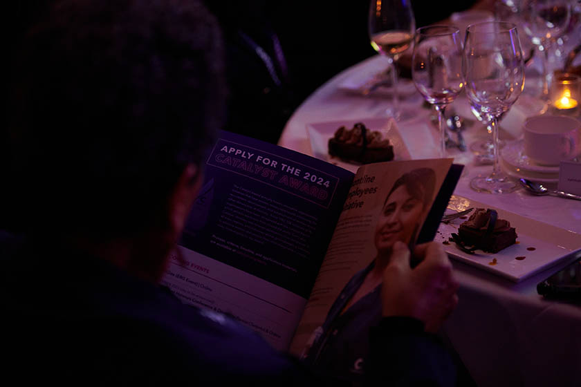 2023 Catalyst Awards attendee looking at the event program at the dinner table