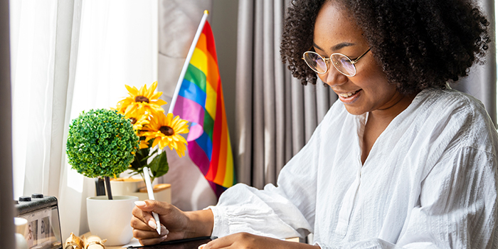 Happy individual at at desk working with a Pride flag